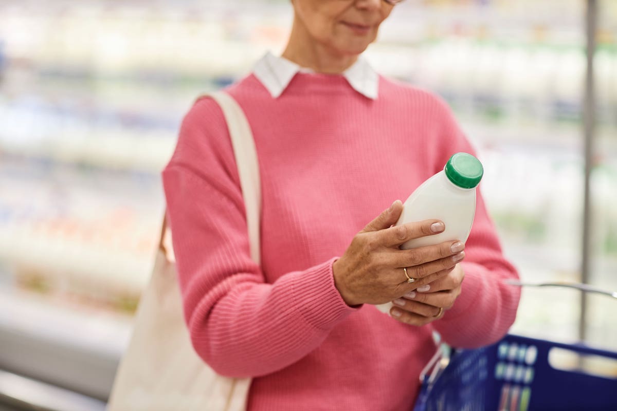 donna al supermercato guarda data di scadenza di una bottiglia di latte